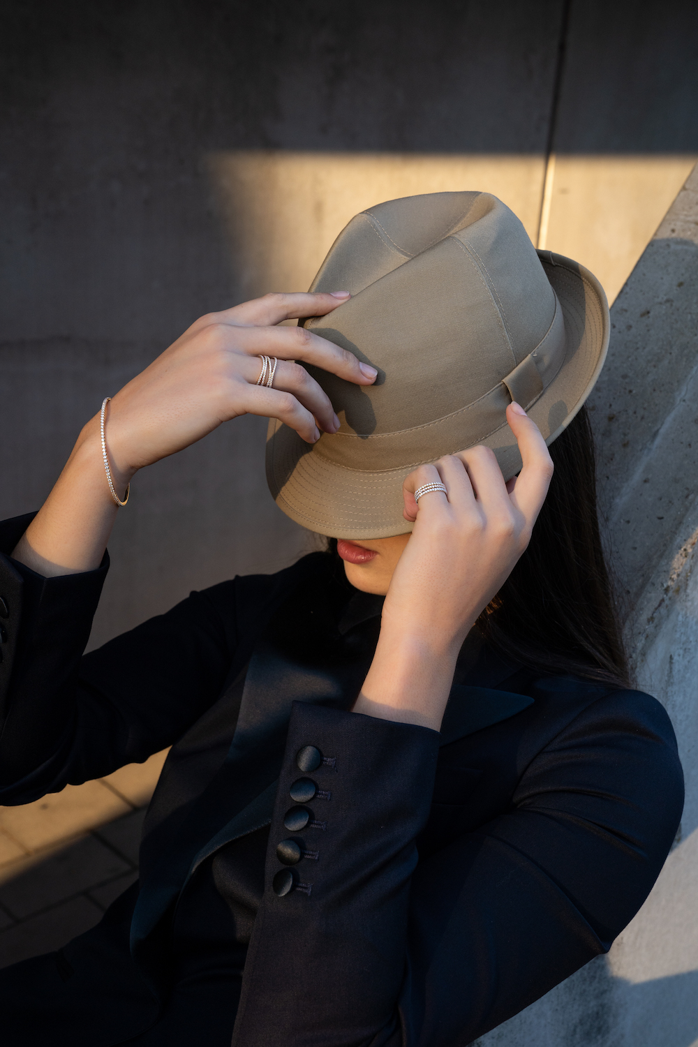 A woman covering her face with a light brown hat, she wears Guinnot jewelry