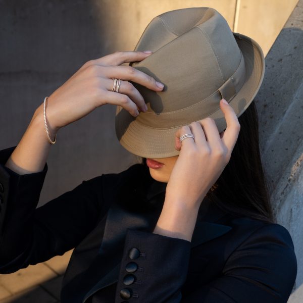 A woman covering her face with a light brown hat, she wears Guinnot jewelry